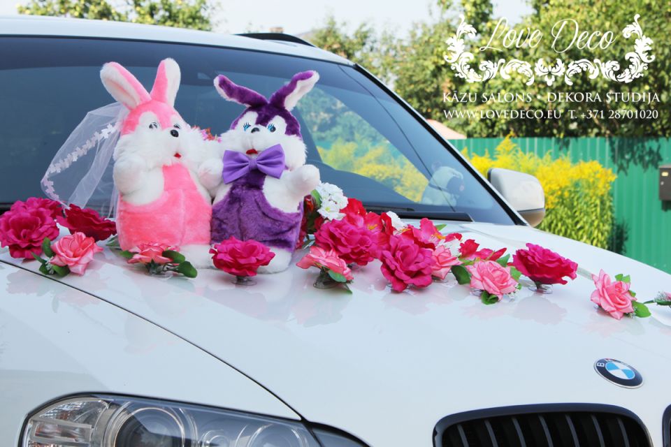 Свадебное украшение машины молодожёнов с парой мягких зайчат и россыпью цветочков по капоту  <br>