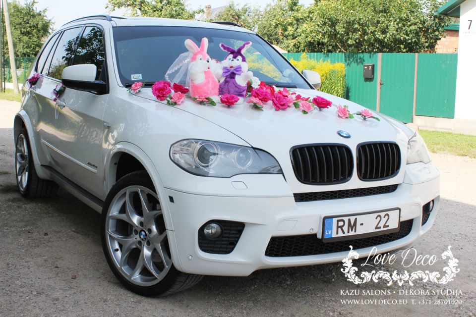 Свадебное украшение машины молодожёнов с парой мягких зайчат и россыпью цветочков по капоту  <br>